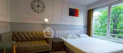 Spacious bedroom with large window and stylish decor in modern apartment.