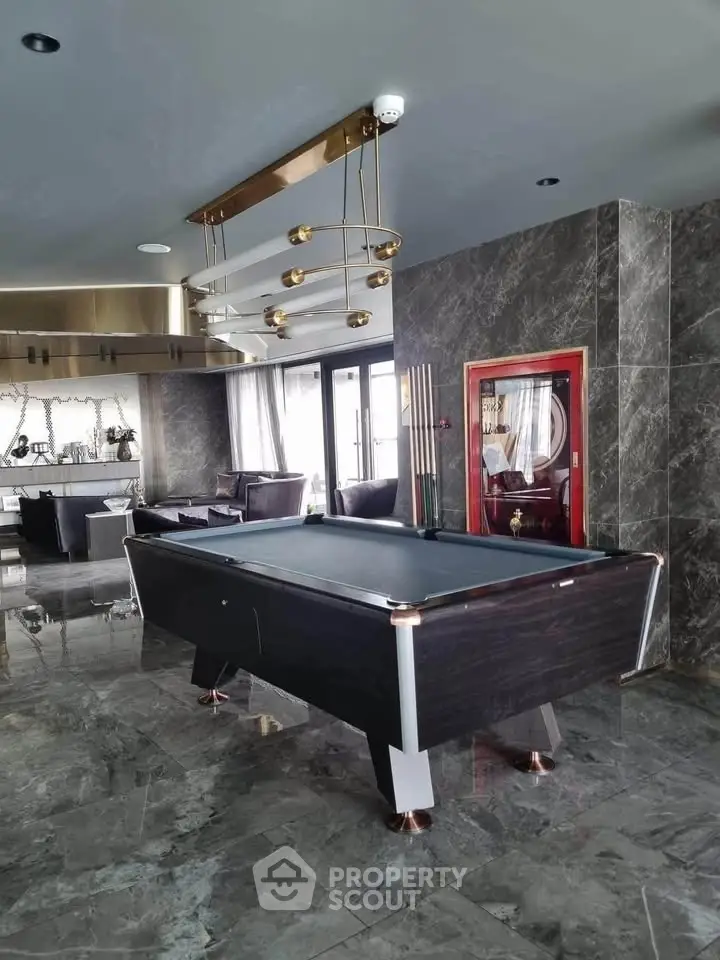Luxurious living room with pool table and modern decor, featuring marble flooring and elegant lighting.