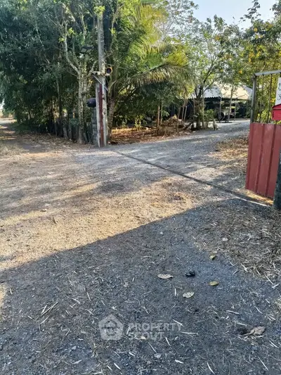 Charming rural property entrance with lush greenery and rustic appeal.