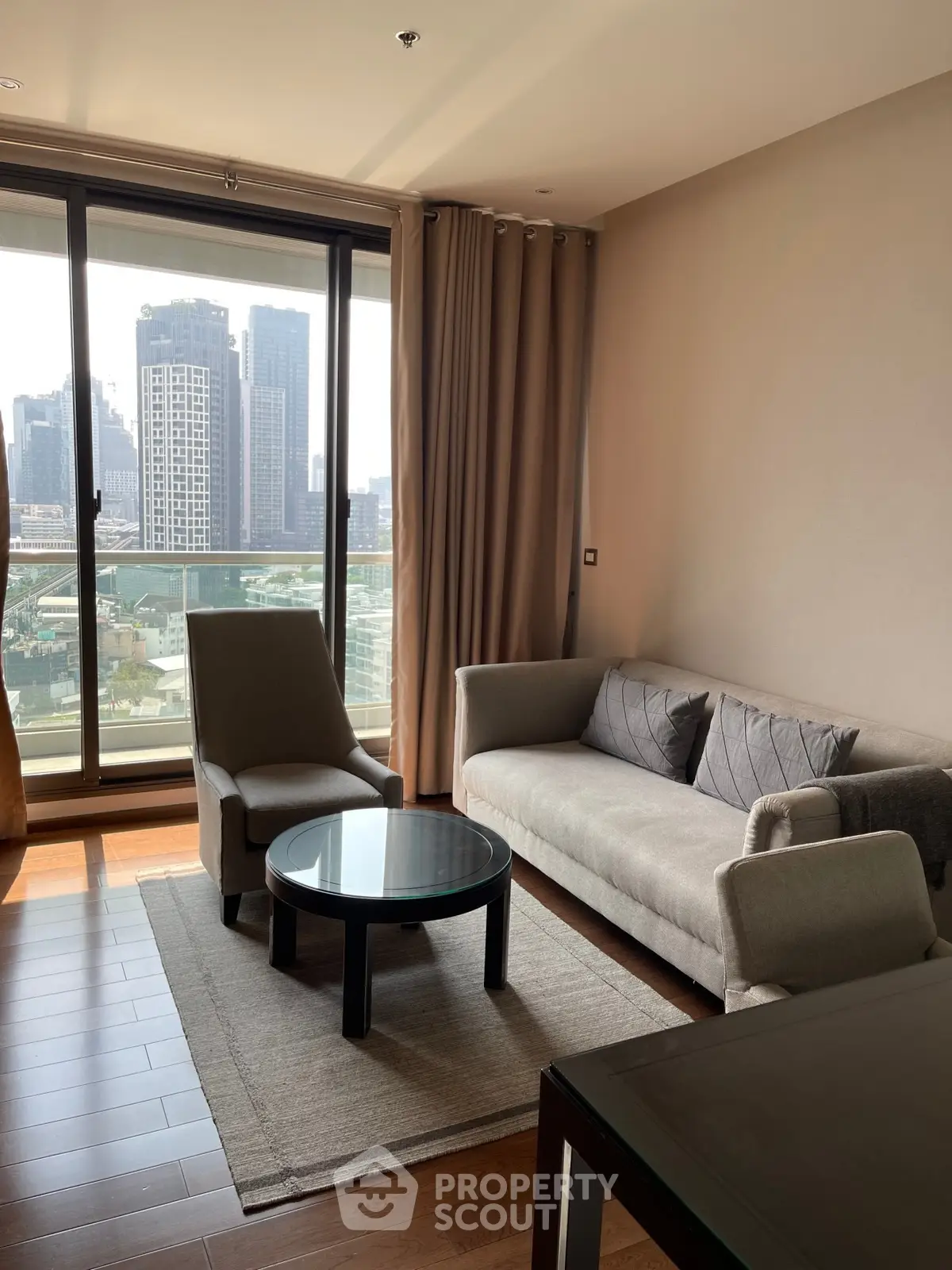 Modern living room with city view, featuring stylish furniture and large windows.