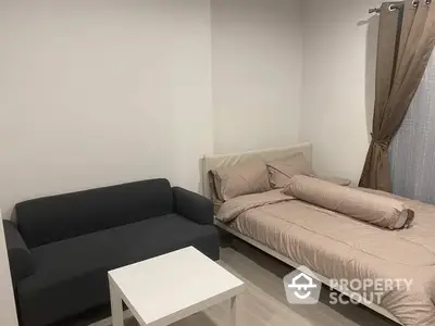 Cozy and modern studio apartment with a comfortable sofa, inviting double bed, and a sleek white coffee table, perfect for urban living.