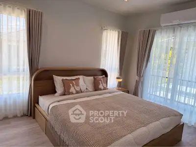 Cozy bedroom with elegant decor and large windows offering natural light
