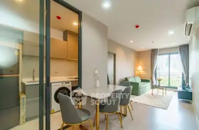 Modern open-plan living room with dining area and washing machine, featuring stylish decor and natural light.