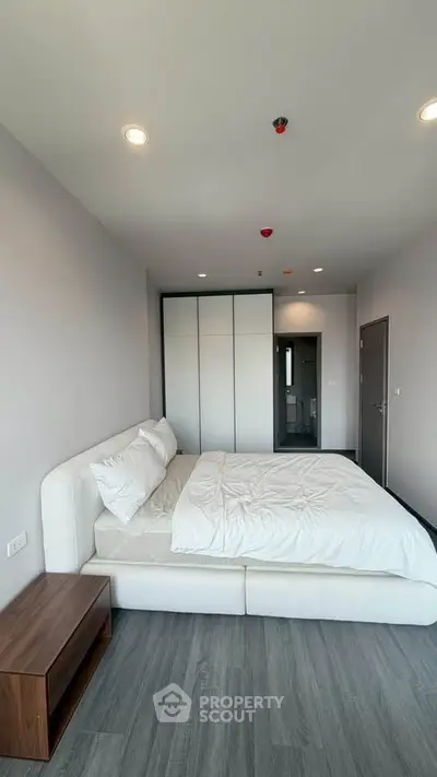 Modern bedroom with sleek design, featuring a comfortable bed and ample closet space.