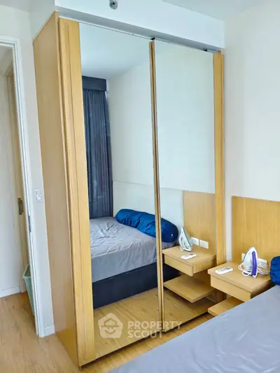 Modern bedroom with mirrored wardrobe and wooden flooring, featuring a cozy bed and sleek design.