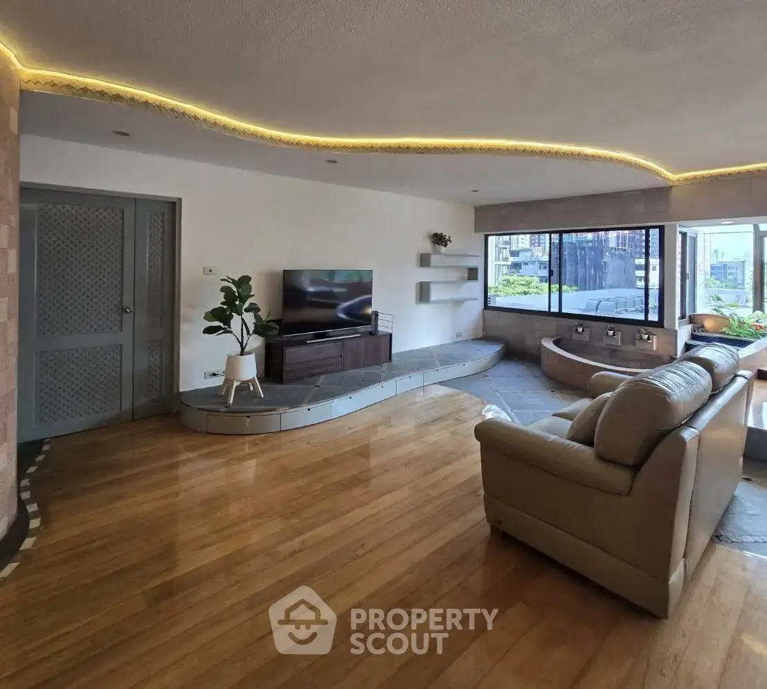 Spacious living room with modern decor and large windows offering city views.
