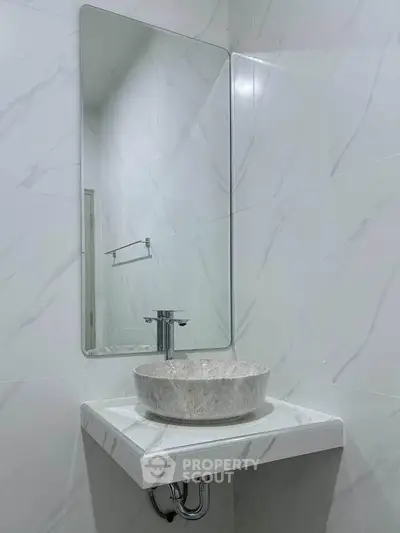 Modern minimalist bathroom with elegant marble sink and sleek mirror design.