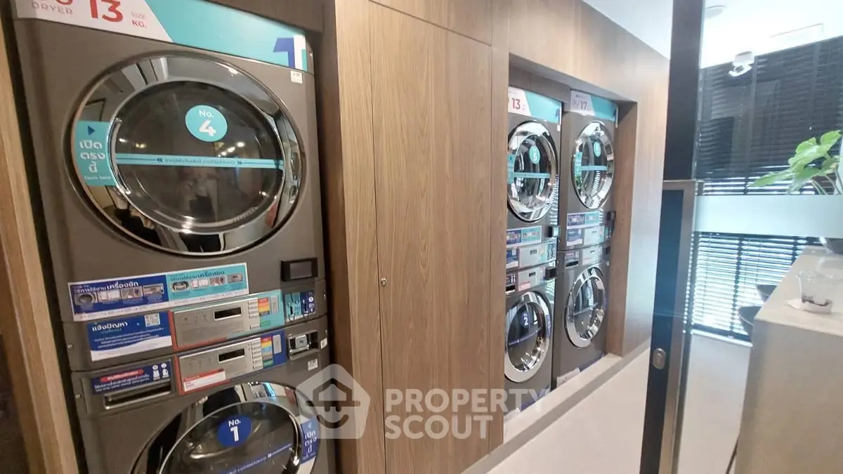 Modern laundry room with multiple washing machines in a sleek apartment building.