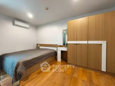 Modern bedroom with wooden flooring and sleek furniture design