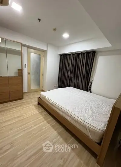 Spacious bedroom with wooden flooring and modern furnishings in a stylish apartment.