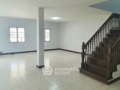 Spacious interior with tiled flooring and wooden staircase, ideal for customization.