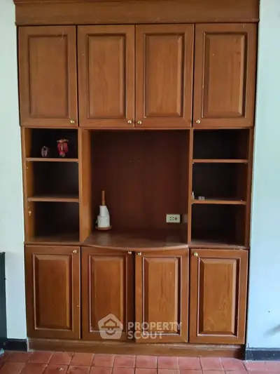 Spacious wooden built-in storage unit with multiple cabinets and shelves, ideal for organizing living spaces.