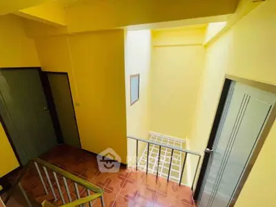 Bright stairwell with yellow walls and wooden flooring in a residential building.