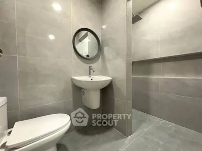 Modern bathroom with sleek gray tiles and round mirror