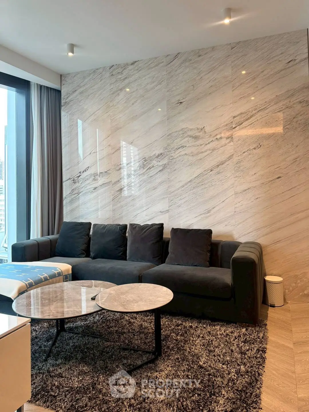 Luxurious modern living room with marble accent wall and plush seating.