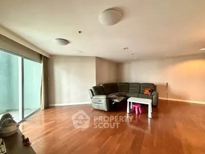 Spacious living room with wooden flooring and large sectional sofa, ideal for family gatherings.