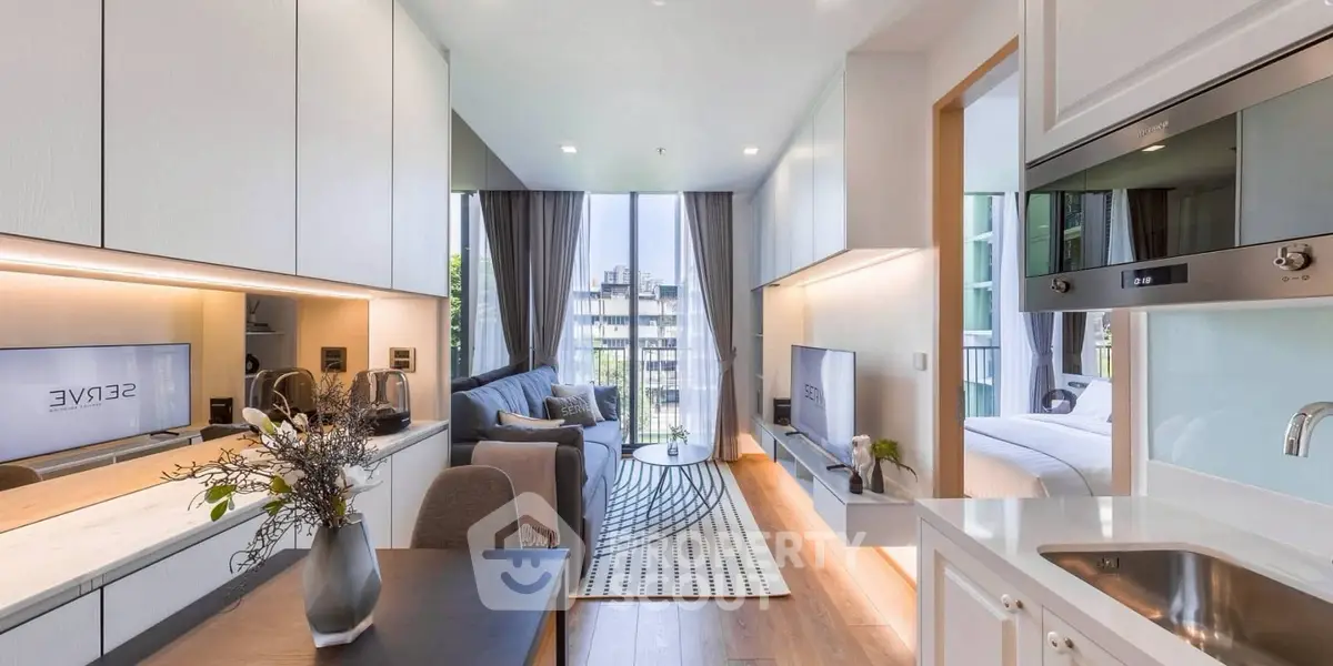 Modern open-plan living room with sleek kitchen and cozy bedroom in luxury apartment.
