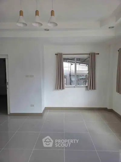 Spacious empty room with large window and modern lighting, perfect for customization.