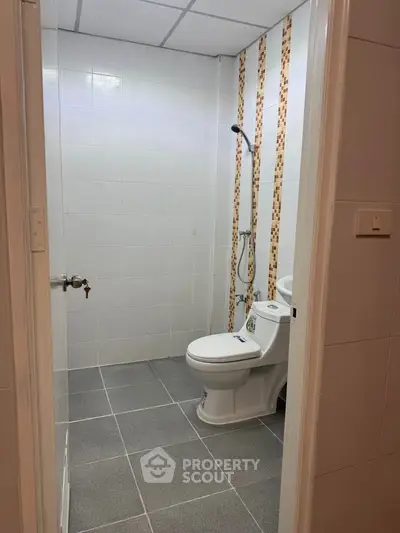 Modern bathroom with tiled walls and floor, featuring a sleek toilet and shower area.