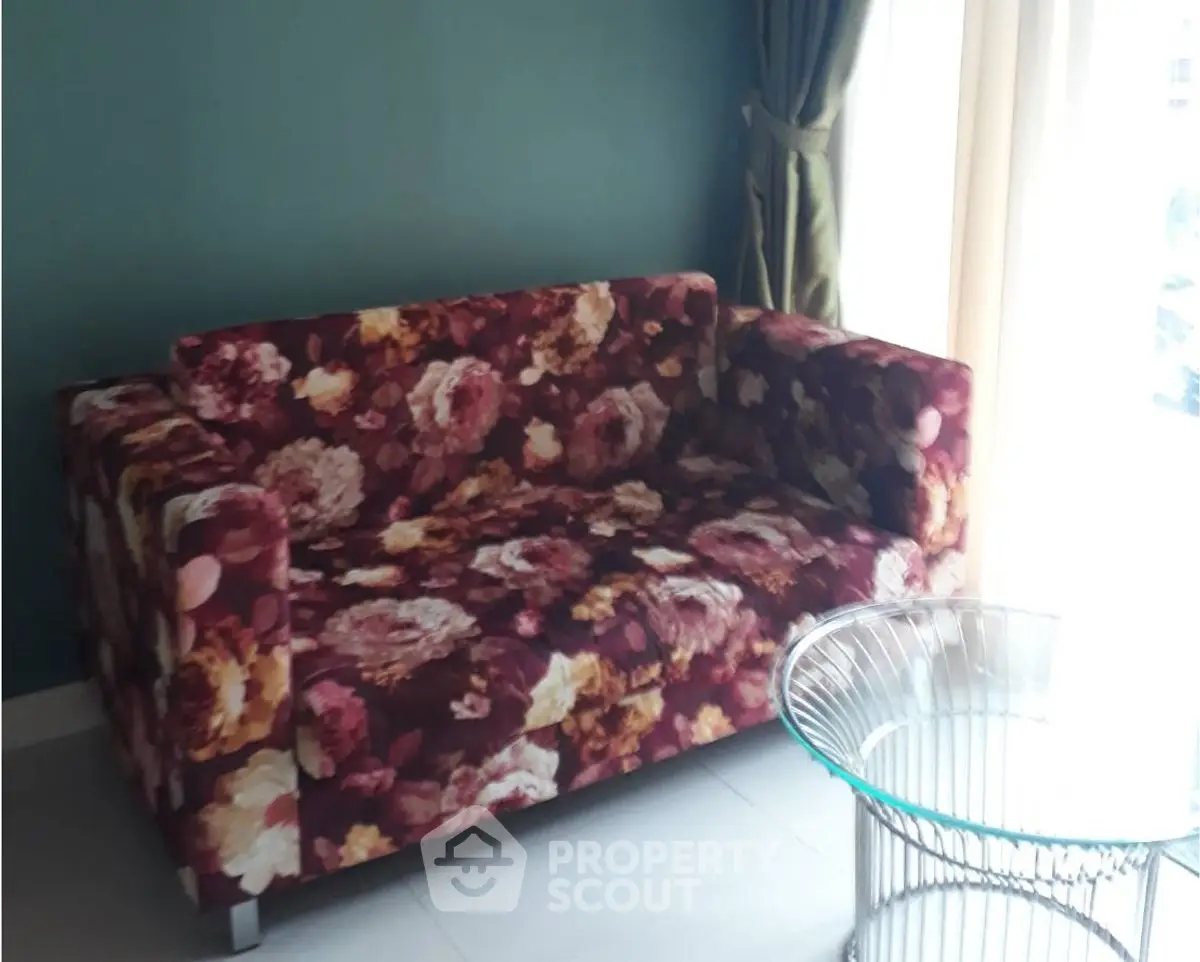 Stylish floral sofa in modern living room with glass table and natural light