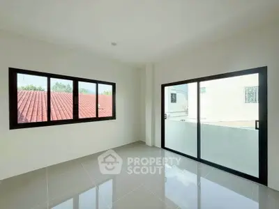 Bright and spacious room with large windows and sliding glass doors offering natural light and outdoor views.