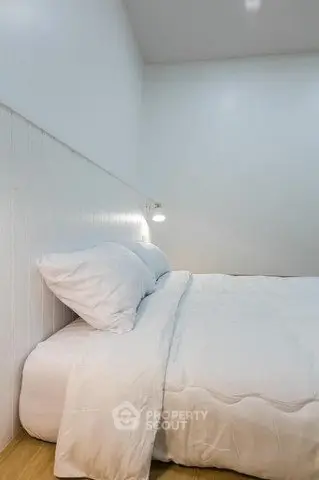 Cozy minimalist bedroom with white bedding and soft lighting, perfect for relaxation.