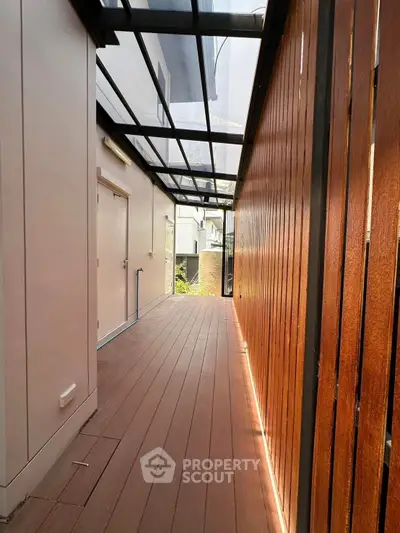 Modern covered balcony with wooden flooring and glass roof