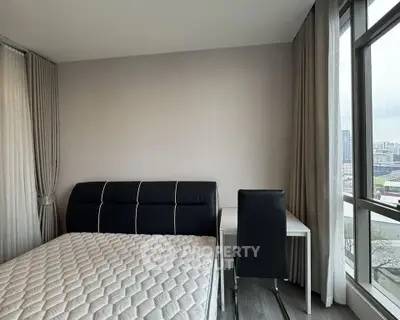 Modern bedroom with city view, featuring a stylish bed and sleek desk for a comfortable living space.