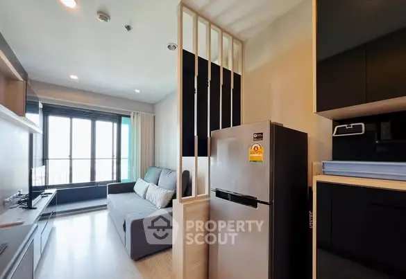 Modern living room with sleek kitchen and cozy sofa in open layout apartment.