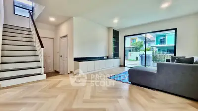 Spacious modern living room with large window and stylish staircase in a contemporary home.