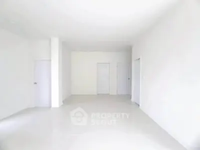 Spacious minimalist interior with white walls and tiled flooring, ideal for customization.