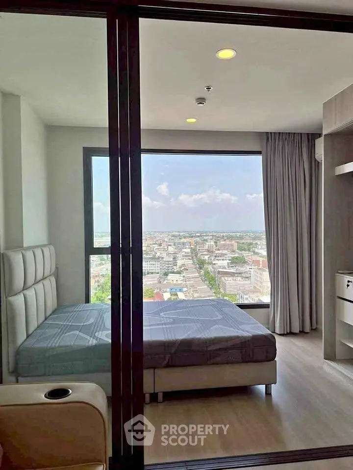 Modern bedroom with large window offering stunning city view in high-rise apartment.