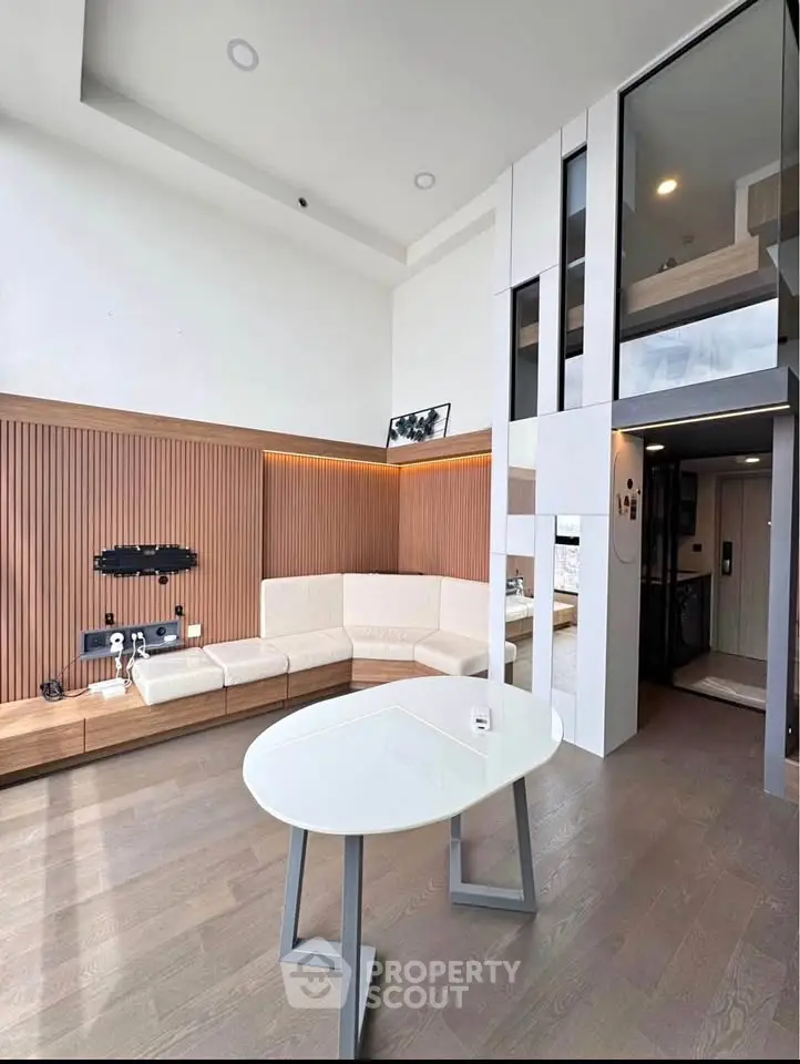 Modern living room with high ceiling and stylish decor, featuring a cozy seating area and sleek wooden accents.