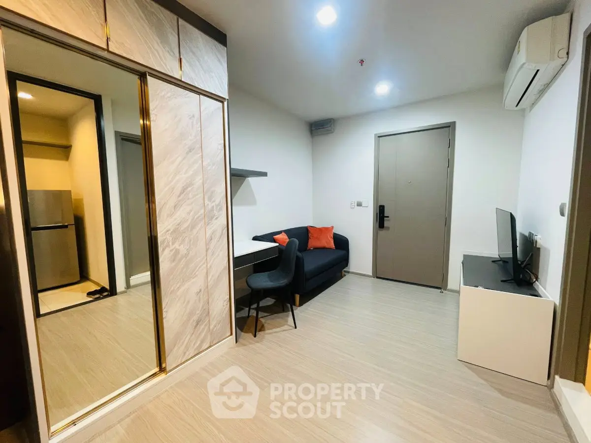 Modern living room with sleek design, featuring a cozy sofa, TV, and mirrored wardrobe in a stylish apartment.
