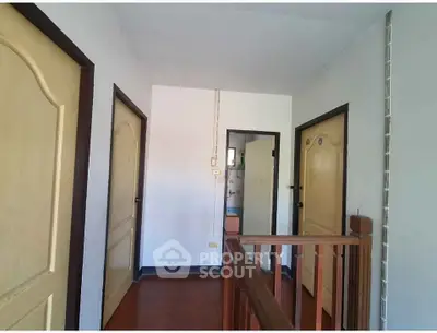 Spacious hallway with wooden railing and multiple doors in a residential property.