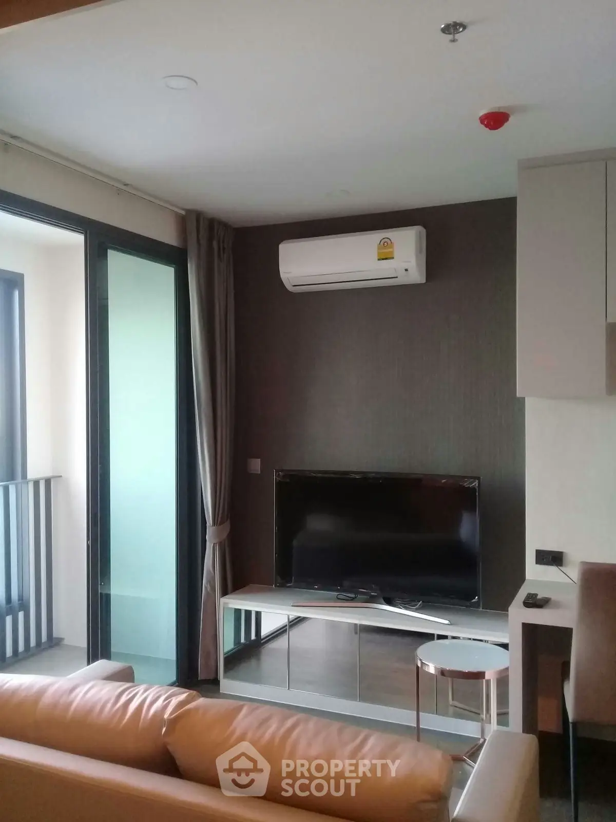 Modern living room with sleek design, featuring a wall-mounted TV and air conditioning, adjacent to a balcony.