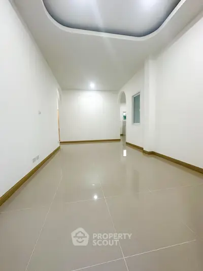 Spacious empty room with glossy tiled floor and modern ceiling design.