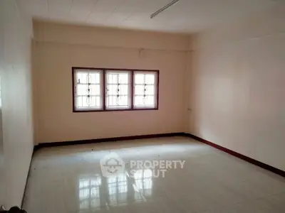 Spacious empty room with large window and tiled floor, perfect for customization.