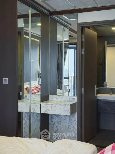 Modern bedroom with marble accents and mirrored wardrobe in a stylish apartment.