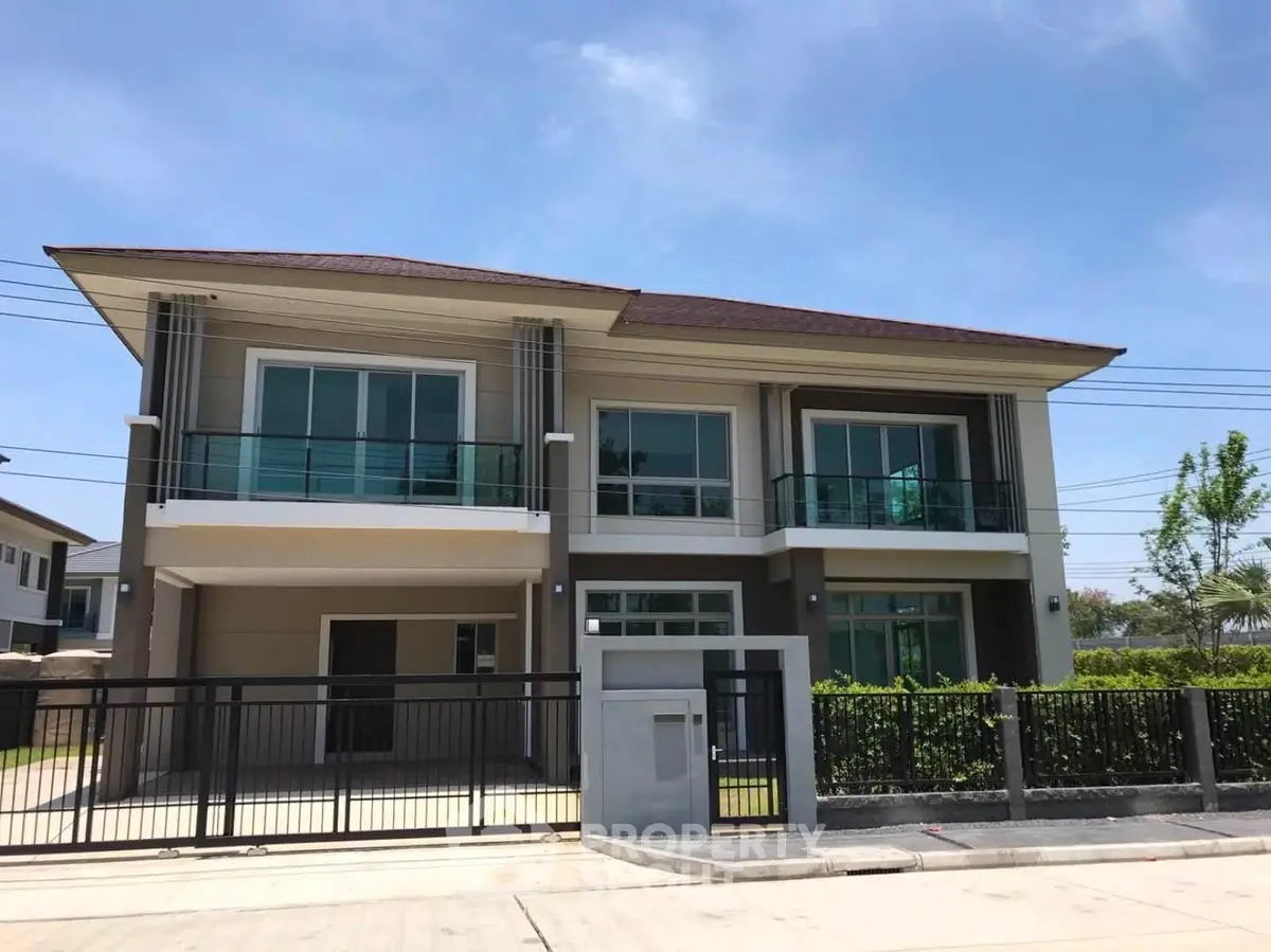 Modern two-story house with large windows and balconies in a suburban neighborhood.