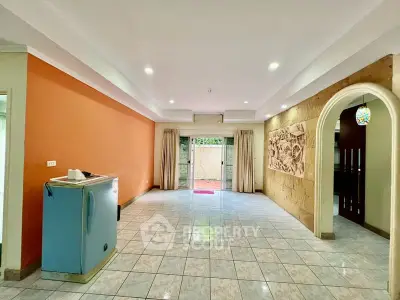 Spacious living room with tiled flooring and vibrant orange accent wall