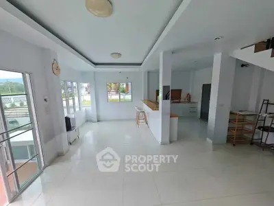 Spacious open-plan living room with modern kitchen and large windows offering natural light.