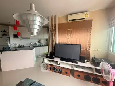 Modern living room with open kitchen, featuring sleek decor and entertainment setup.