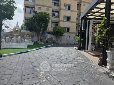 Charming apartment building exterior with landscaped garden and paved driveway