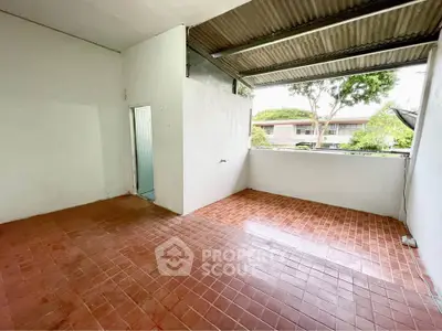 Spacious tiled balcony with partial roof and garden view, ideal for outdoor relaxation.