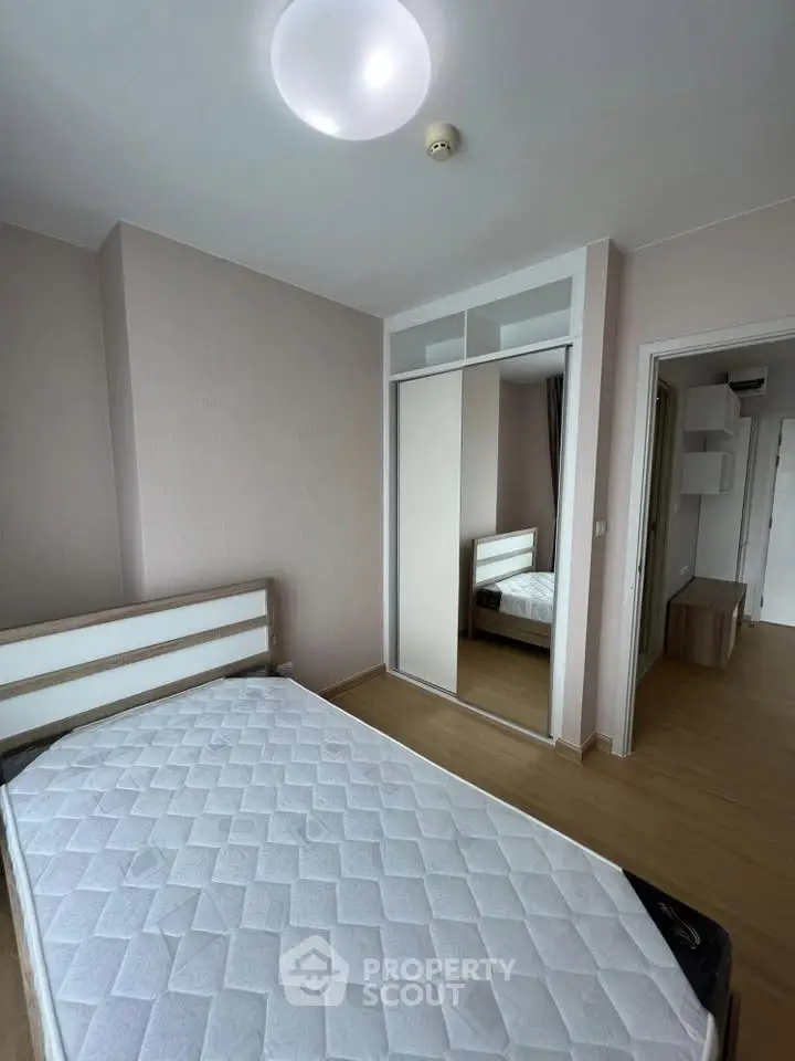 Modern bedroom with minimalist design, featuring a comfortable bed and mirrored wardrobe for ample storage.