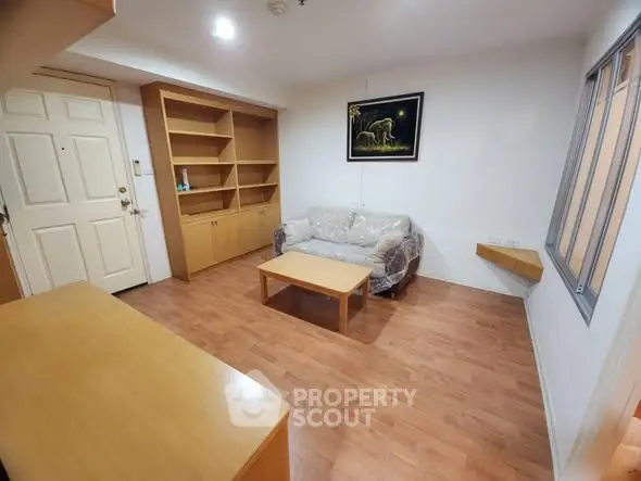 Cozy living room with wooden flooring and built-in shelves, perfect for relaxation.
