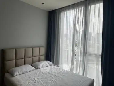Modern bedroom with large window and city view, featuring a stylish headboard and sheer curtains.
