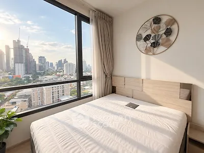 Modern bedroom with large windows offering stunning city views and elegant decor.