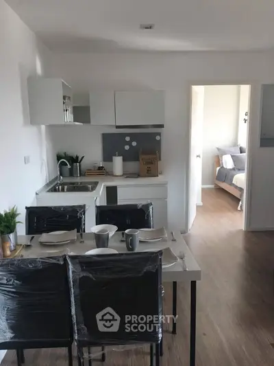 Modern open-layout kitchen with dining area leading to a cozy bedroom, perfect for urban living.